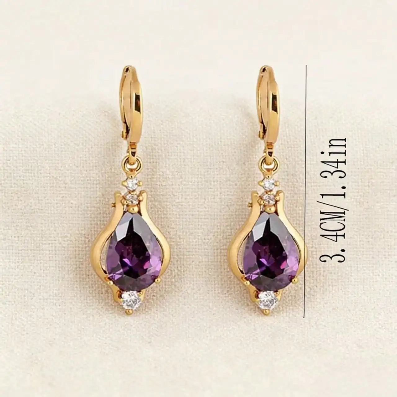 Gold earrings with purple stone on a beige background