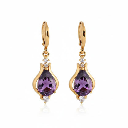 Gold earrings with purple stone on a beige background