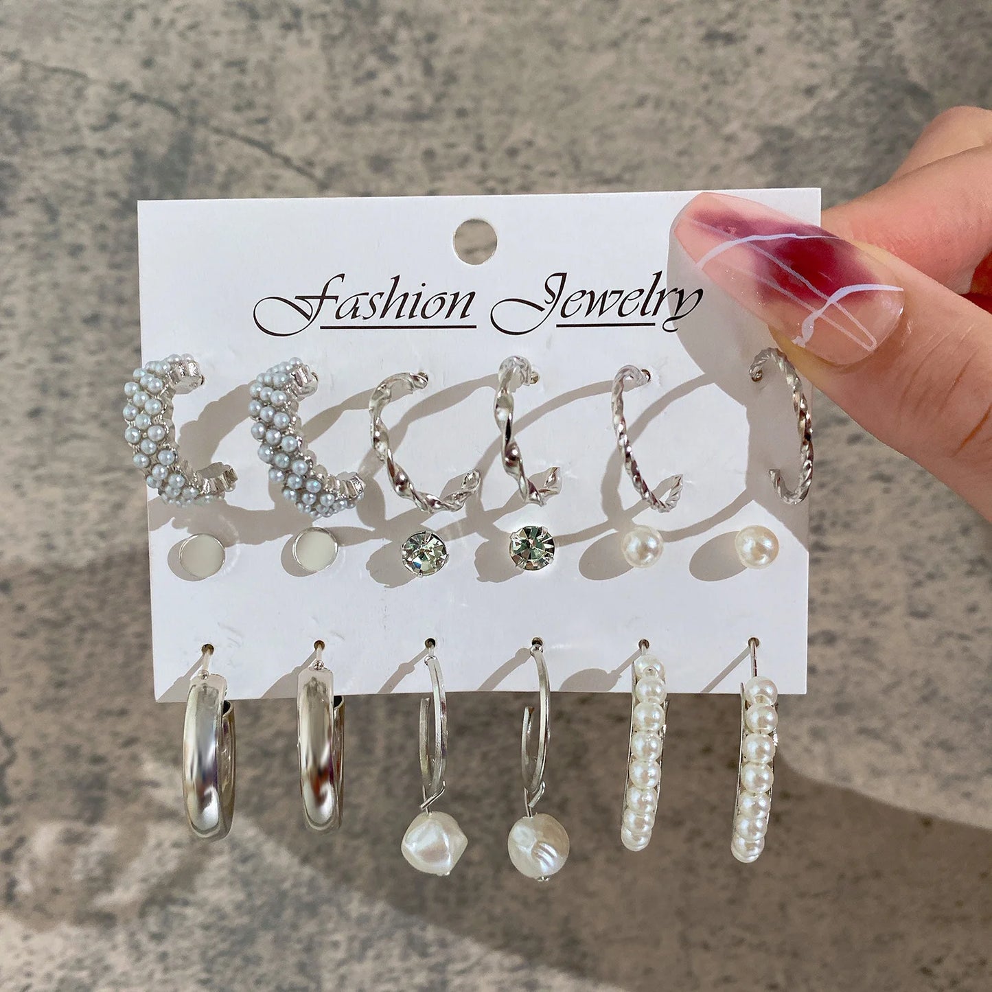 Set of earrings on a 'Fashion Jewelry' card held by a hand.