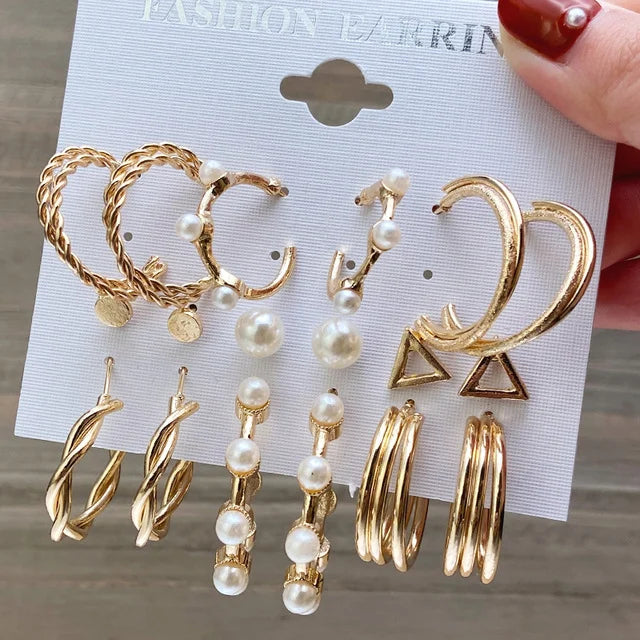 Set of gold and pearl earrings on a card held by a hand.