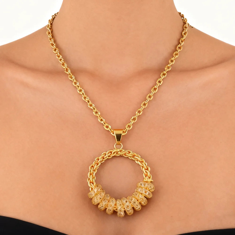 Gold chain necklace with a circular pendant on a person against a white background