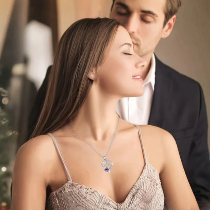 Woman wearing a necklace with a heart pendant, standing close to a man.