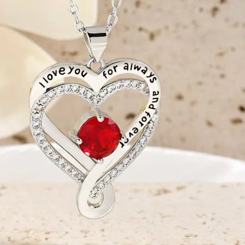Heart-shaped silver pendant with red gemstone and 'I love you for always and forever' text on a beige background.