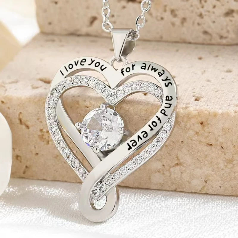 Silver heart-shaped pendant with engraved text on a beige surface