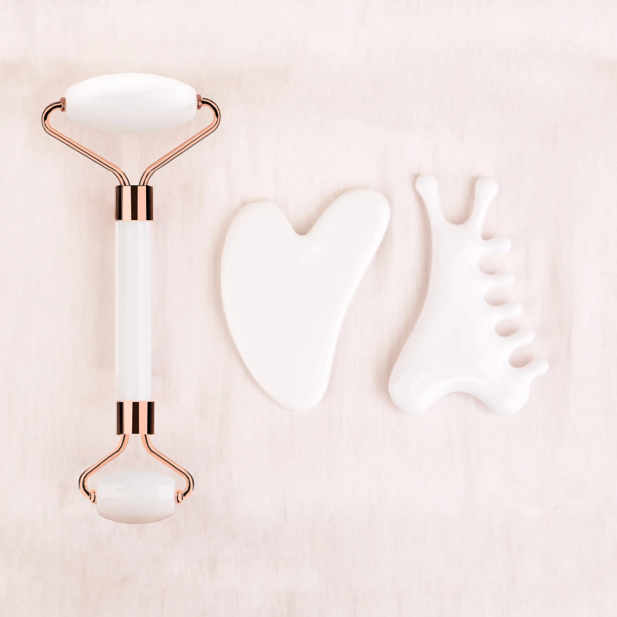 White facial roller with rose gold accents on a light pink background