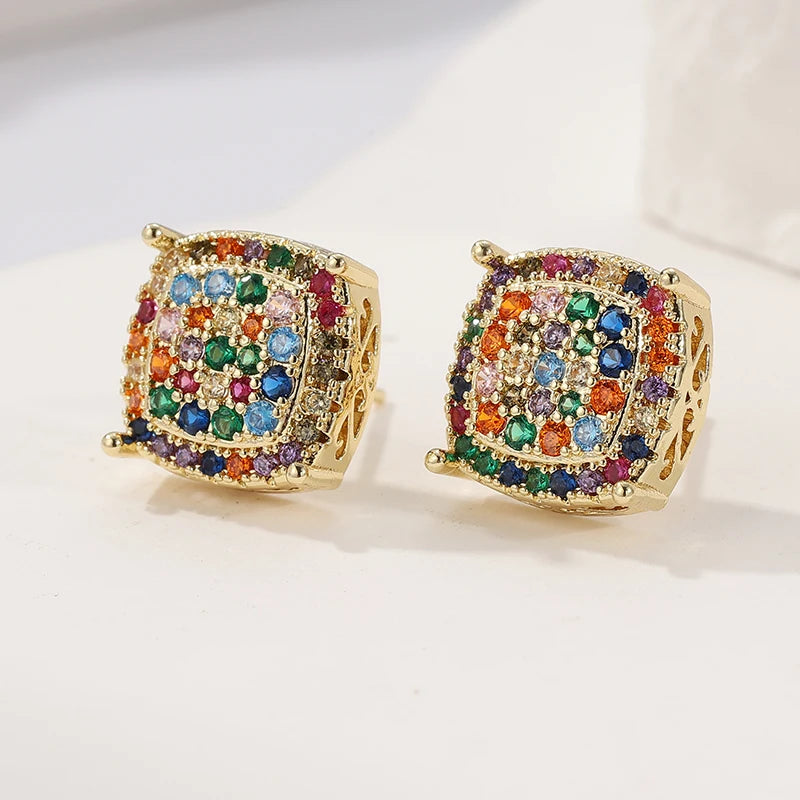 A pair of gold square stud earrings adorned with a colorful array of multicolored rhinestones, displayed on a clean white surface.