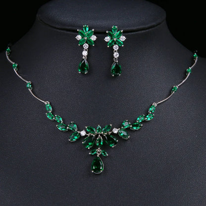 Emerald green gemstone jewelry set including a necklace and matching earrings displayed on a black jewelry bust. The set features silver-tone metal settings with clear rhinestones and green teardrop and marquise-cut stones.