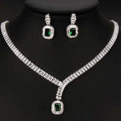 Silver-tone jewelry set featuring a necklace and matching earrings with rectangular green gemstones surrounded by clear stones, displayed on a black mannequin bust.