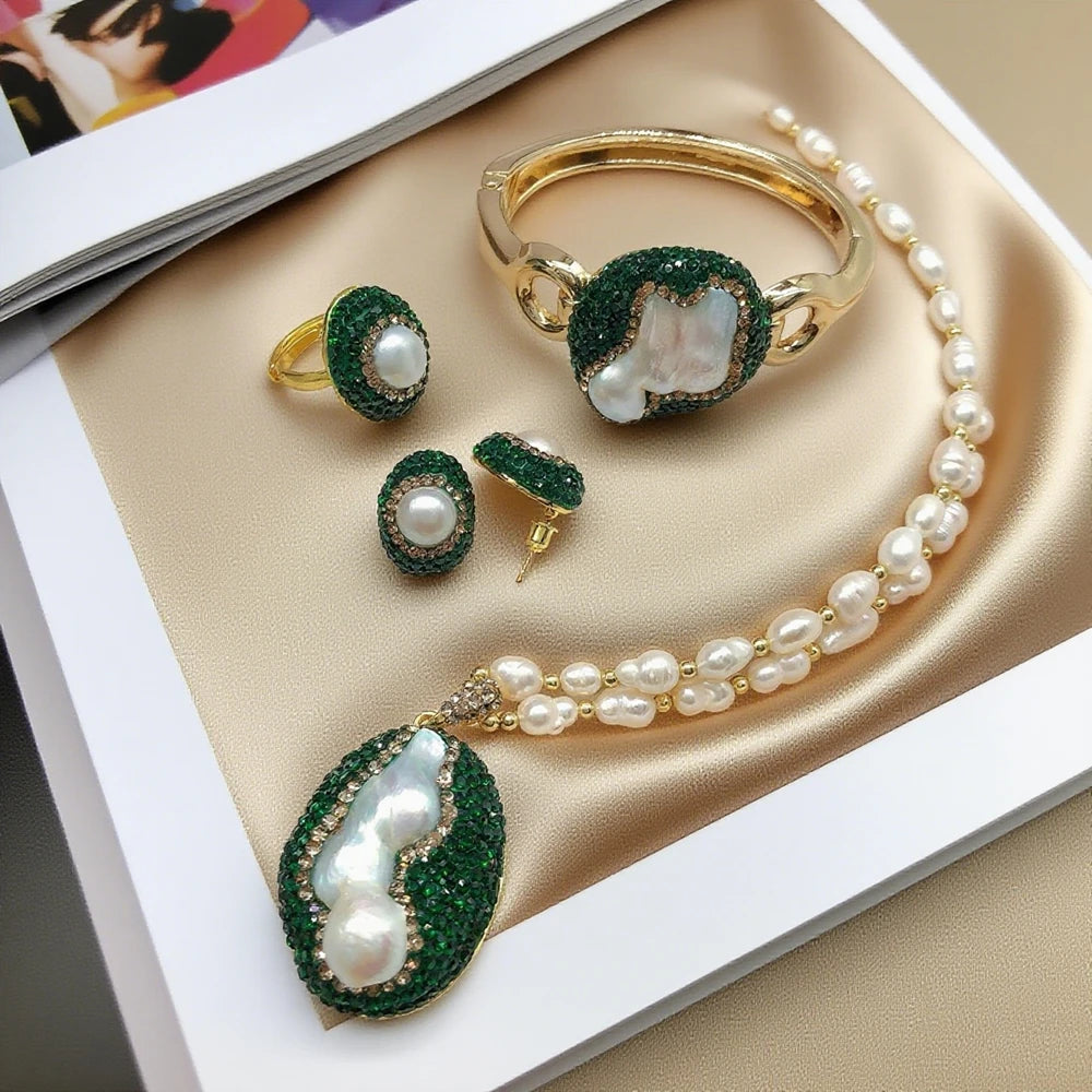 Jewelry set with pearls and green gemstones on a beige surface