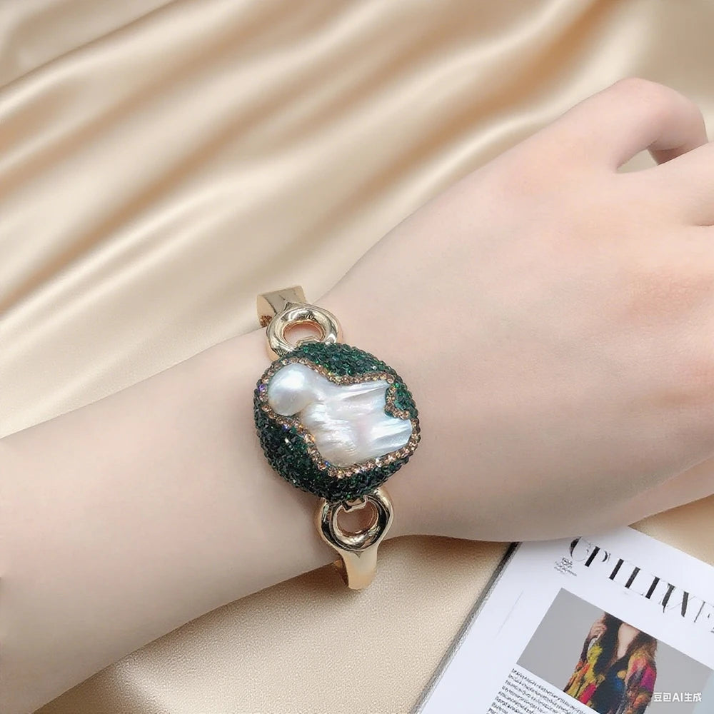 Bracelet with a large pearl-like stone on a hand against a beige fabric background