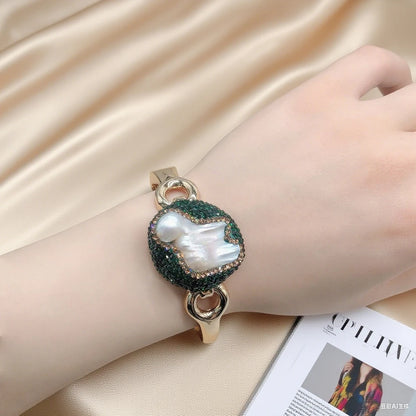 Bracelet with a large pearl-like stone on a hand against a beige fabric background
