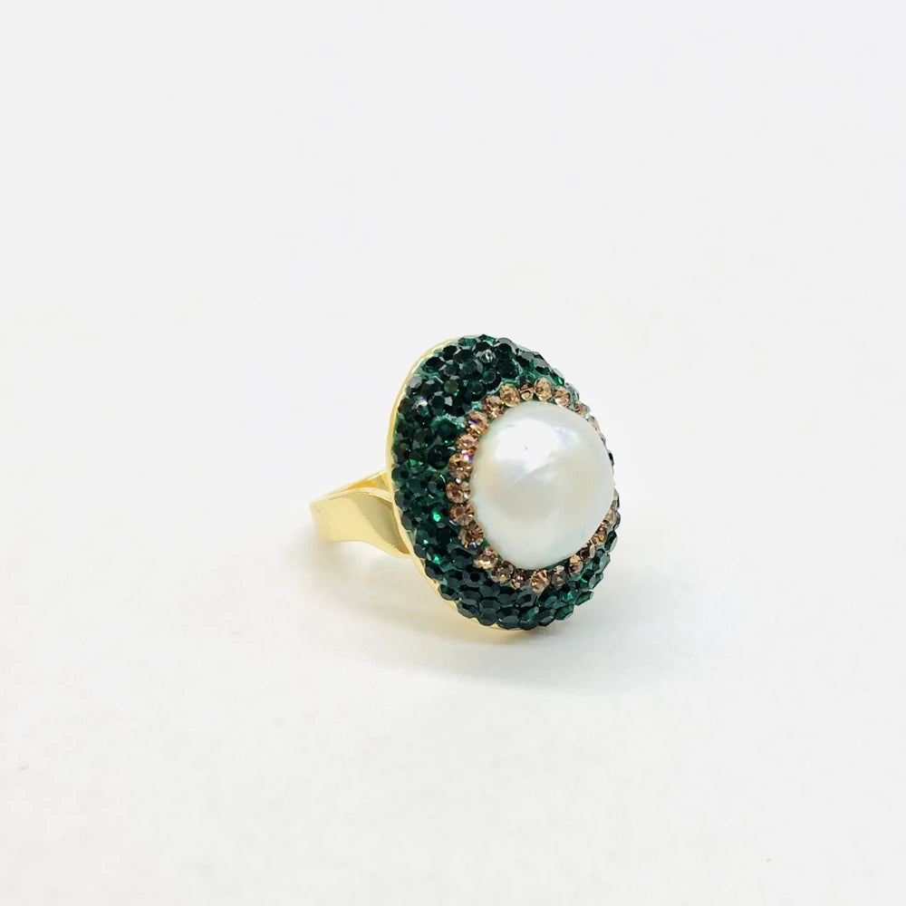 Ring with a pearl and green gemstones on a white background
