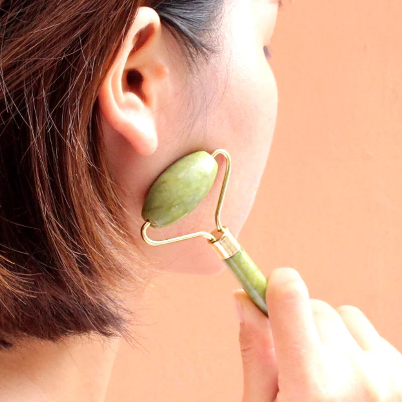 Person using a jade roller on their face with a blurred background