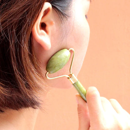 Person using a jade roller on their face with a blurred background