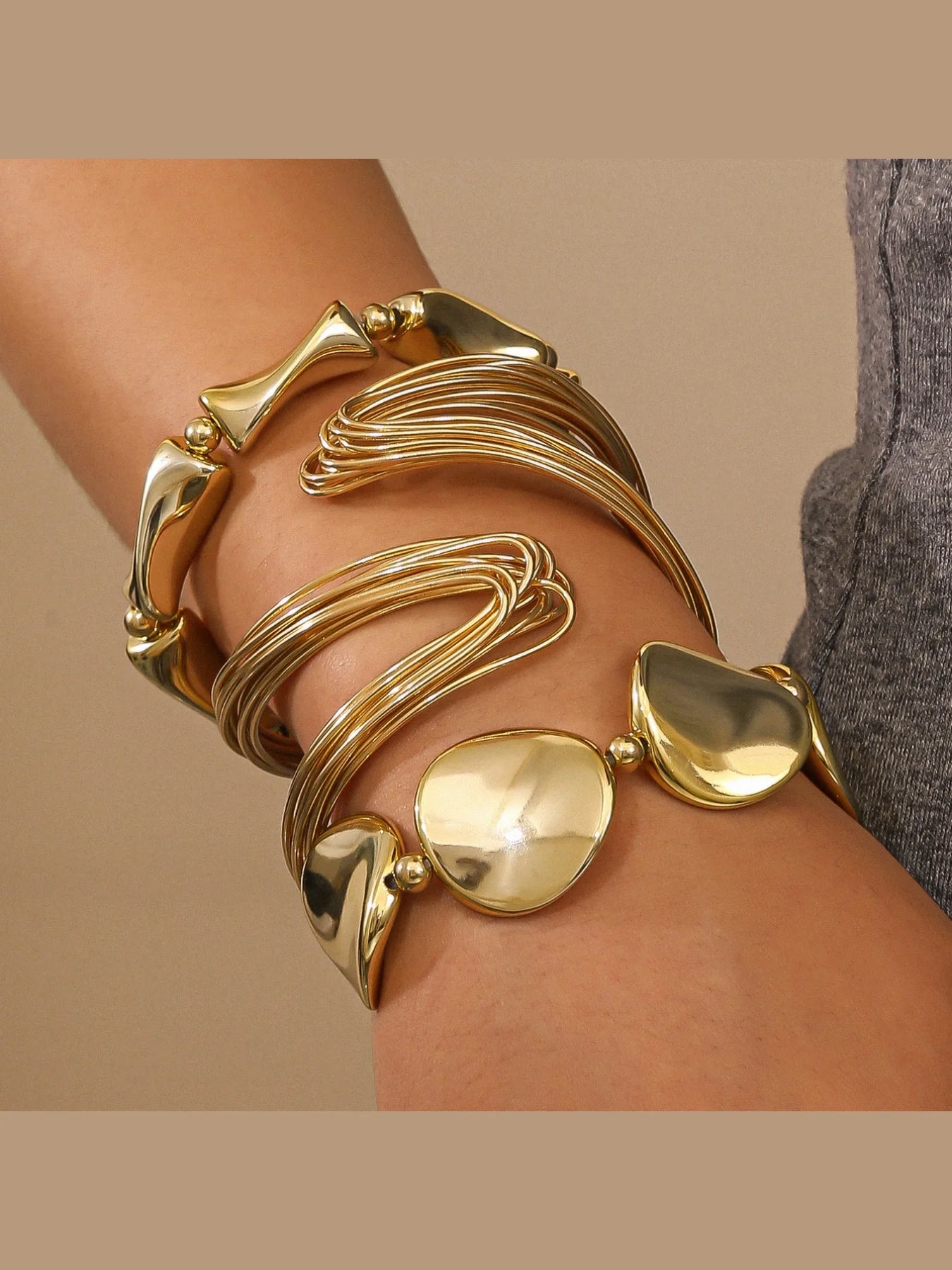 Gold bracelet on a wrist with a neutral background