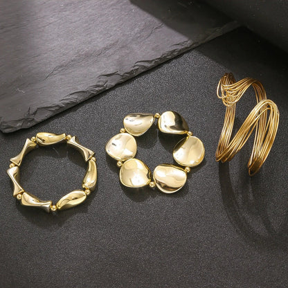 Three gold bracelets on a dark slate surface