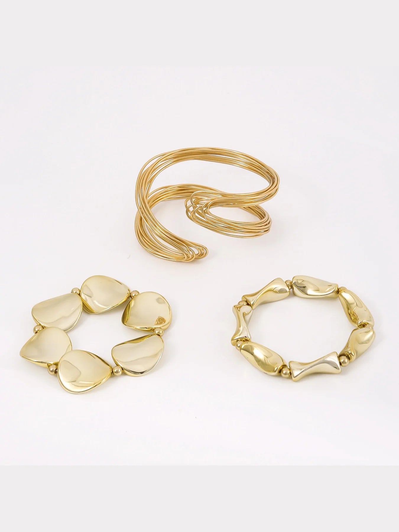 Three gold bracelets on a white background