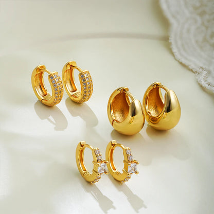 Set of gold hoop earrings on a light background