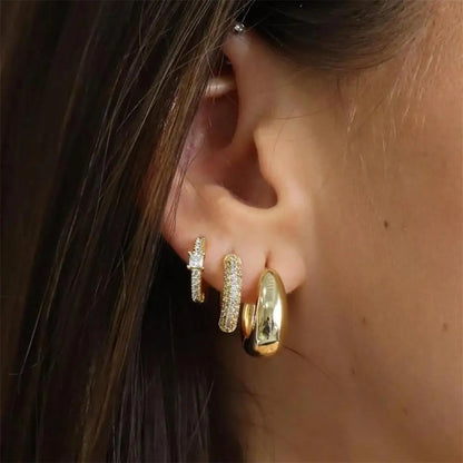 Close-up of an ear wearing gold hoop earrings with a blurred background