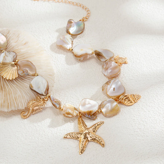 Pearl and gold necklace with starfish charm on a white shell background