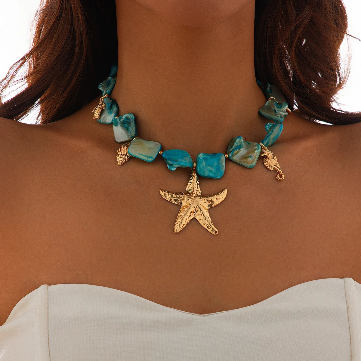 Necklace with turquoise stones and a gold starfish pendant on a person
