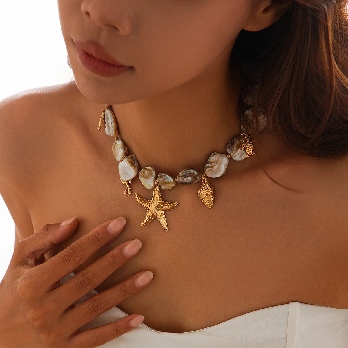 Woman wearing a necklace with starfish and shell designs on a white background