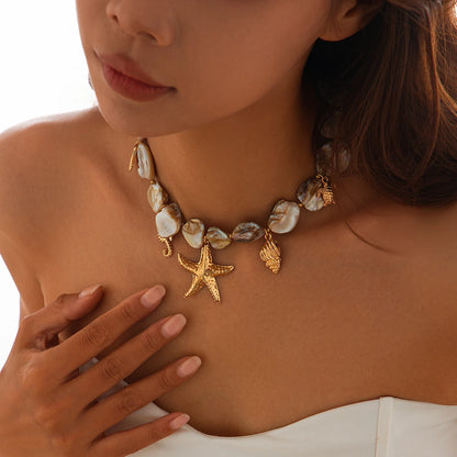 Woman wearing a necklace with starfish and shell designs on a white background