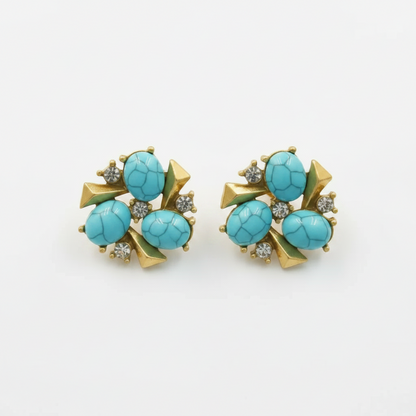 A pair of vintage gold-tone stud earrings featuring oval turquoise cabochons and small clear crystal accents, displayed on a neutral light gray background.