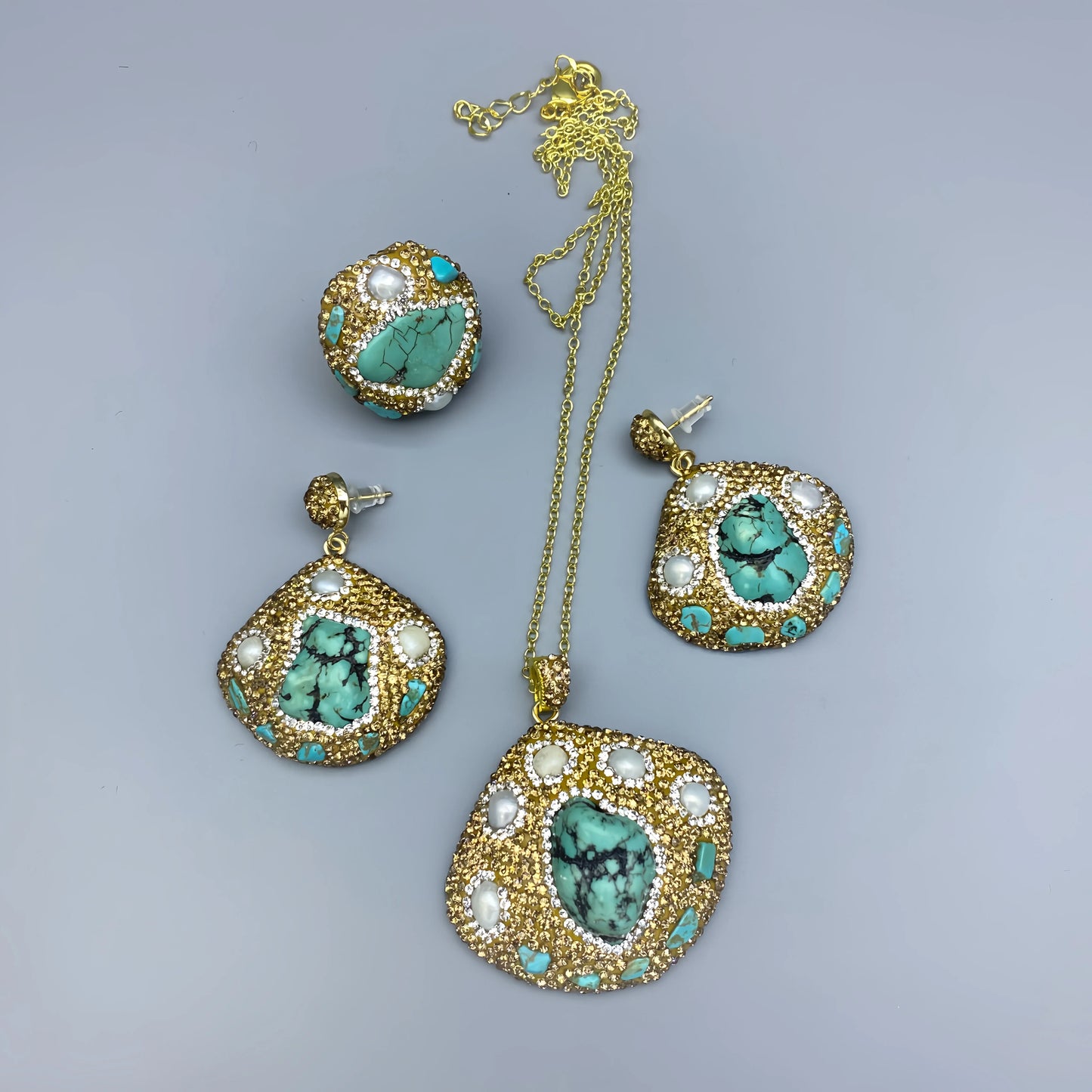 Jewelry set with gold, turquoise, and pearl accents on a gray background