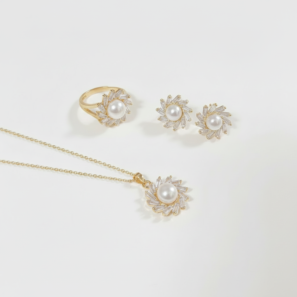 A gold jewelry set featuring a ring, a pendant necklace, and a pair of stud earrings, each designed with a central white pearl surrounded by small clear stones in a sunburst pattern, displayed on a clean white background.